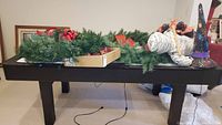 Photo showing multiple holiday decorations including Christmas wreaths and Halloween decor on a table