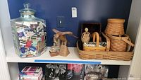 Glass jar full of matchbooks, wooden carved bird figurine, small glass paperweight, rectangular and round woven baskets.