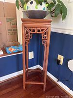 Full view of the wooden plant stand showing carved decorative fretwork and overall structure.