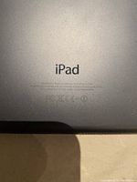 Back view of the space gray Apple iPad Mini showing the iPad branding and regulatory info.