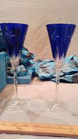 Pair of blue crystal champagne/wine glasses with etched floral/star designs visible, placed next to a ruler for size reference.