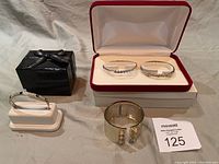 Lot arranged showing all four silver-tone bracelets with rhinestone detailing, including pair in a red-trimmed velvet presentation box and separate cuff bracelets.