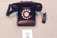 Front view of black rotary dial Bell telephone with handset resting on base and coiled cord, showing telephone number dial
