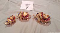 Three decorated brass elephant figurines with colorful crystals in red, blue, and purple embellishments