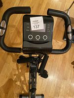 Close-up top view of the LCD monitor on the exercise bike with control buttons and hand pulse sensors on handlebars.