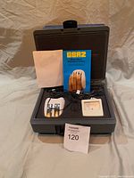 Top-down photo of open carrying case showing GSR Trainer, analog meter, electrode cables, and user manual