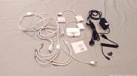 Full overview of the lot showing multiple cables and adapters laid out on a gray surface including white and black cables, Apple iPad dock connector cables, power adapter, and RCA connectors.