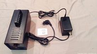 Top view of the black smoke machine and power adapter with cables laid out on a white surface.