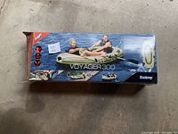 Box packaging for the Voyager 300 inflatable boat depicting usage with adults and child paddling.