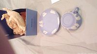 Wedgwood cup and saucer set, light blue jasperware with white relief figures, taken out of box showing both items and tissue wrapping.