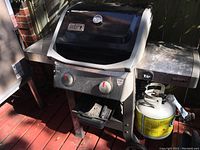 Front view of grill showing lid, control panel, burners and attached propane tank