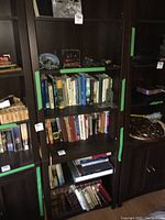 Full view of leaning bookshelf with books and decorative items, showing scratches on shelves