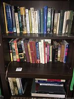 Full view of two bookshelf shelves containing a mix of hardcover and paperback books focusing on history, war, and novels with various dust jackets and binding conditions.