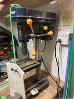 Front angle view of the Mastercraft 8-inch drill press showing the worktable, feed handles with yellow knobs, and power cord.