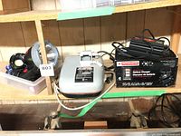 Photo showing Mastercraft wet sharpener in center, Motomaster battery charger to right, assorted flashlights in container to left