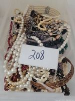 Full view of tangled vintage necklaces including cream faux pearls and mixed bead types showing overall condition and variety.