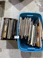 Two boxes of vinyl records and albums, one plastic blue bin with assorted records, one cardboard box with record books and albums