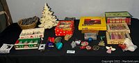 Full lot overview showing multiple boxed and loose Christmas decorations, ceramic trees, and electric train set box