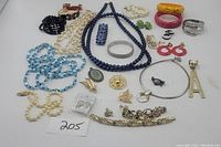 Full view of costume jewelry lot showing over 25 pieces including necklaces, earrings, bracelets, brooches, and pendants arranged on white background.