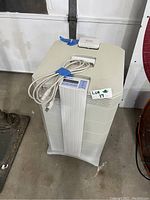 Front view of IQ Air air purifier unit with control panel and power cord on top.