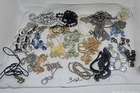View showing entire lot of 20 assorted necklaces in different styles and materials, spread on white background.