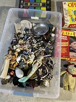Plastic bin filled with assorted small animal and character figures including fish, birds, and soldiers.