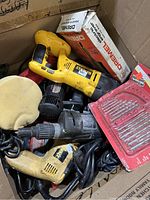 Box containing DeWalt cordless drill, Dremel rotary tool box, black drill, drill bits, and accessory pads