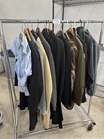 Clothing on rack showing multiple jackets including jean jackets, sweaters, and blazers in various colors and styles
