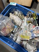 Blue plastic bin containing multiple glass mason jars and numerous seal tops inside plastic bags and wrapped in newspaper.