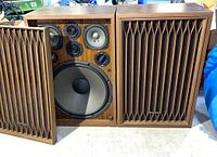 Two Kenwood speakers side by side, one with grille removed to show drivers