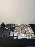 Full lot overview showing PS2 console, Sega Genesis Saga system, multiple controllers, Sega Genesis game cartridges, and PS2 game discs.