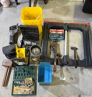 Overall view of assorted tools on floor including saw table frame, tools, yellow cable reel, and containers.