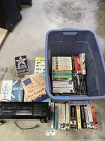 Wide photo showing Sony cassette player next to a tote bin of various VHS and audio cassette tapes