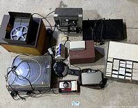 Photo showing all items grouped on floor, including reel-to-reel recorder, turntable, cameras, headphones, Vizio DVD player, and small electronic devices