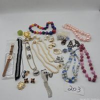 Full overview of vintage costume jewelry including necklaces, earrings, brooches, bracelet, and watch arranged on white background.