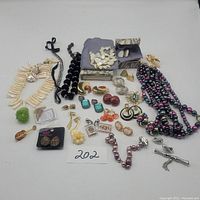 Overview of the entire jewelry lot showing mixed pieces of necklaces, earrings, brooches, and bracelets arranged with boxes