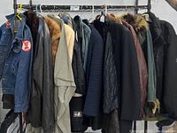 Various men's and women's jackets and fur coats hanging side by side on a rack showing different styles and materials.