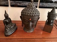Front view of all three bronze Buddha sculptures arranged side by side