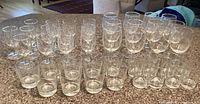 Full set of various size etched glassware arranged on countertop: wine glasses, sherry glasses, rocks glasses, juice glasses.