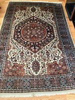 Full view of rectangular wool rug showing overall pattern, colors, fringe and borders