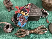 Metal compartment box with multicolored beaded strap, small woven basket and brass dorje visible
