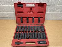Photo showing 27 black impact sockets including two extensions in a red case, arranged in two rows with molded cutouts for storage.