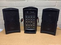 Front view of mixer/amplifier unit centered between two satellite speakers