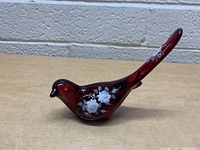 Side view of the red glass bird showing white hand painted rose flowers and floral designs.