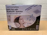 Front view of the boxed Home NetWerks Bath Fan with Bluetooth Speaker, LED Light and Night Light, showing branding, key features, and an image of a relaxed woman.