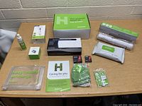 Full view of all items in Humana branded health kit arranged on table including thermometer, sanitizer, pulse oximeter, masks, wipes, gloves and accessories.