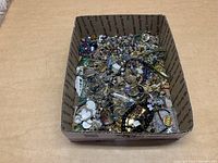 Top overview of box with assorted jewelry items showing different bead types and metallic pieces