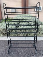 Front view of the black metal shoe rack showing all 8 tiers and caster wheels.