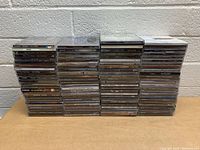 Front view of the stacked CDs in multiple columns on a table against a white brick background.