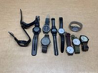 Overview of 10 wrist watches laid out on a flat surface showing different strap colors, types, and watch faces.